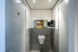 Moderne toiletruimte aan de De Ruijterkade met een wastafel, spiegel en zeepdispensers.